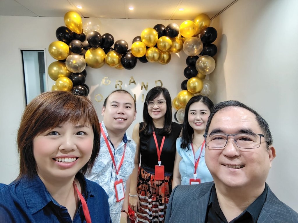 Dougles Chan and the team taking a selfie in front of the grand opening balloon display